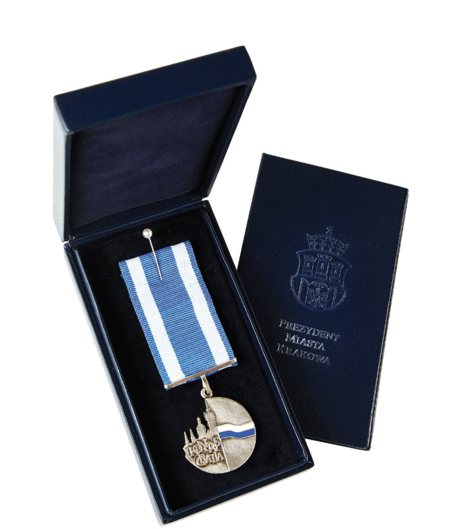 (124–126) Awers i rewers odznaki „Honoris Gratia” nadawanej osobom i instytucjom zasłużonym dla Krakowa. Ustanowiona w 2004 r. zarządzeniem
Prezydenta Miasta Krakowa, pozostaje w prezydenckiej gestii. Średnica 40 mm, wykonana z białego metalu z emaliowaną, biało-błękitną wstęgą,
przywieszona na wstążce także eksponującej barwy miasta. Projekt Jerzy Nowakowski (z zasobów UMK)