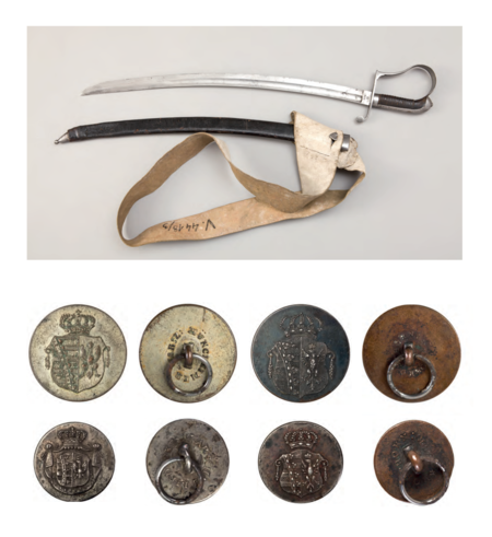 Szabla z epoki, wzór austriacki, z pendentem (pasem podtrzymującym zakładanym przez ramię, jak na sąsiedniej grafice)
oraz guziki mundurowe z herbem Księstwa Warszawskiego – na tarczy dwudzielnej w lewym polu herb Saksonii złożony z dziesięciu
pasów, na których w skos ruciana korona (władcą Księstwa Warszawskiego był król Saksonii Fryderyk August I Wettyn),
natomiast w polu prawym orzeł w koronie, w charakterystycznej dla ówczesnych czasów stylistyce
(Muzeum Narodowe w Krakowie, nr inw. MNK V-4418/1-3; MNK V-619/1-4;
reprodukcje wykonane przez Pracownię Fotograficzną MNK)