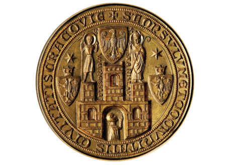 (347) Najstarsza pieczęć miasta Krakowa, jednocześnie pieczęć radziecka – w otoku napis:
S[IGILLVM] CONSVLVM ET COMVNITATIS CIVITATIS CRACOVIE
(pieczęć rajców i mieszczaństwa [pospólstwa] miasta Krakowa). Powstała z przerobienia
pieczęci miasta i wójta krakowskiego (zob. il. 001 oraz il. 047), po obniżeniu w 1312 r. rangi
wójtowskiego urzędu. Znana z odcisków w wosku przy dokumentach z lat 1343, 1425 i 1430.
Więcej szczegółów oraz reprodukcje z oryginałów zob. il. 052–057. W 1895 r. powstała wierna
replika stempla tej pieczęci (zob. il. 002), która jest przechowywana w Archiwum Narodowym
w Krakowie. Kolejna pełnowartościowa replika powstała już w czasach odrodzonego
po 1990 r. samorządu, należy do Urzędu Miasta Krakowa i jest wykorzystywana
dla oprawy szczególnie uroczystych dokumentów – na zdjęciu widoczny
ten właśnie stempel (z zasobów UMK)