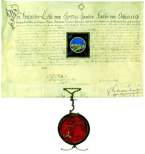 Fot. 53. Miasta satelickie Krakowa Podgórze. Dokument wydany w 1808 roku w Wiedniu, mocą którego cesarz Franciszek I nadał miastu Podgórze nowy herb, opisując i ukazując jego wizerunek. Herb w swojej treści zawiera alegoryczne przesłanie związane z legendą słupów Herkulesa, w otoku napis: * SIGLLUM REGIAE LIBERAE * QUE CIVITATIS PODGORZE * – PIECZĘĆ KRÓLEWSKIEGO WOLNEGO MIASTA PODGÓRZA – oraz zbliżenie wizerunku herbu zamieszczone na następnej stronie (Archiwum Narodowe w Krakowie, sygn. perg. 1093)