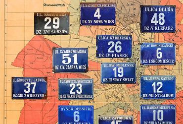 Fot. 37. Na Planie orientacyjnym stoł. król. miasta Krakowa wydanym przez Budownictwo Miejskie w 1925 r. (pierwsze wydanie w 1916 r.) kolekcja zachowanych jeszcze na frontonach kamienic emaliowanych tabliczek orientacyjnych z numerami domów według wzoru wprowadzanego sukcesywnie w okresie międzywojennym (numeracja domów wprowadzona w 1881 r. co do zasady nie zmieniała się, podział na dzielnice katastralne także był stabilny, stąd możliwość równoległego utrzymywania dawnego – jeszcze z roku 1881 – i nowego wzoru tych tabliczek. Powyżej przedstawiono stan istniejący do roku 1941, kiedy to do granic Krakowa przyłączono szereg terenów, z których utworzono nowe dzielnice katastralne, o kolejnych numerach od XIII do LII. W miarę integrowania tych nowych dzielnic z organizmem miejskim i tam pojawiły się tabliczki z numerami domów według tego wzoru. Sytuacja zmieniła się w związku z wprowadzeniem w 1954 r. podziału administracyjnego miasta na 6 dzielnic oraz zlikwidowaniem w 1955 r. podziału miasta na dzielnice katastralne – wówczas to wprowadzono nowy wzór tabliczek z nazwami nowych dzielnic (plan miasta: Biblioteka Jagiellońska, sygn. M 41/95)